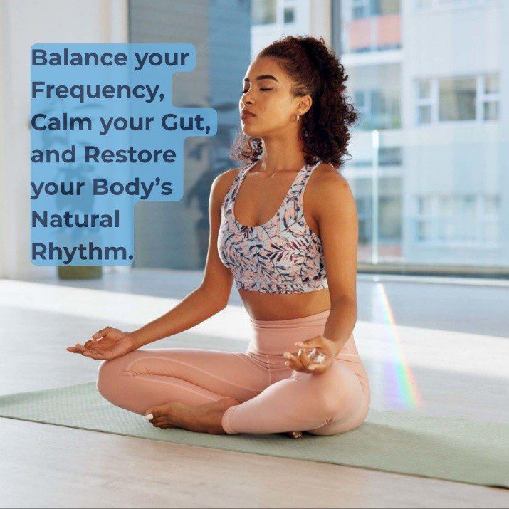 A South African woman sitting cross-legged in a peaceful meditation pose on a yoga mat, next to a light blue text bubble that reads: "Balance your Frequency, Calm your Gut, and Restore your Body's Natural Rhythm."